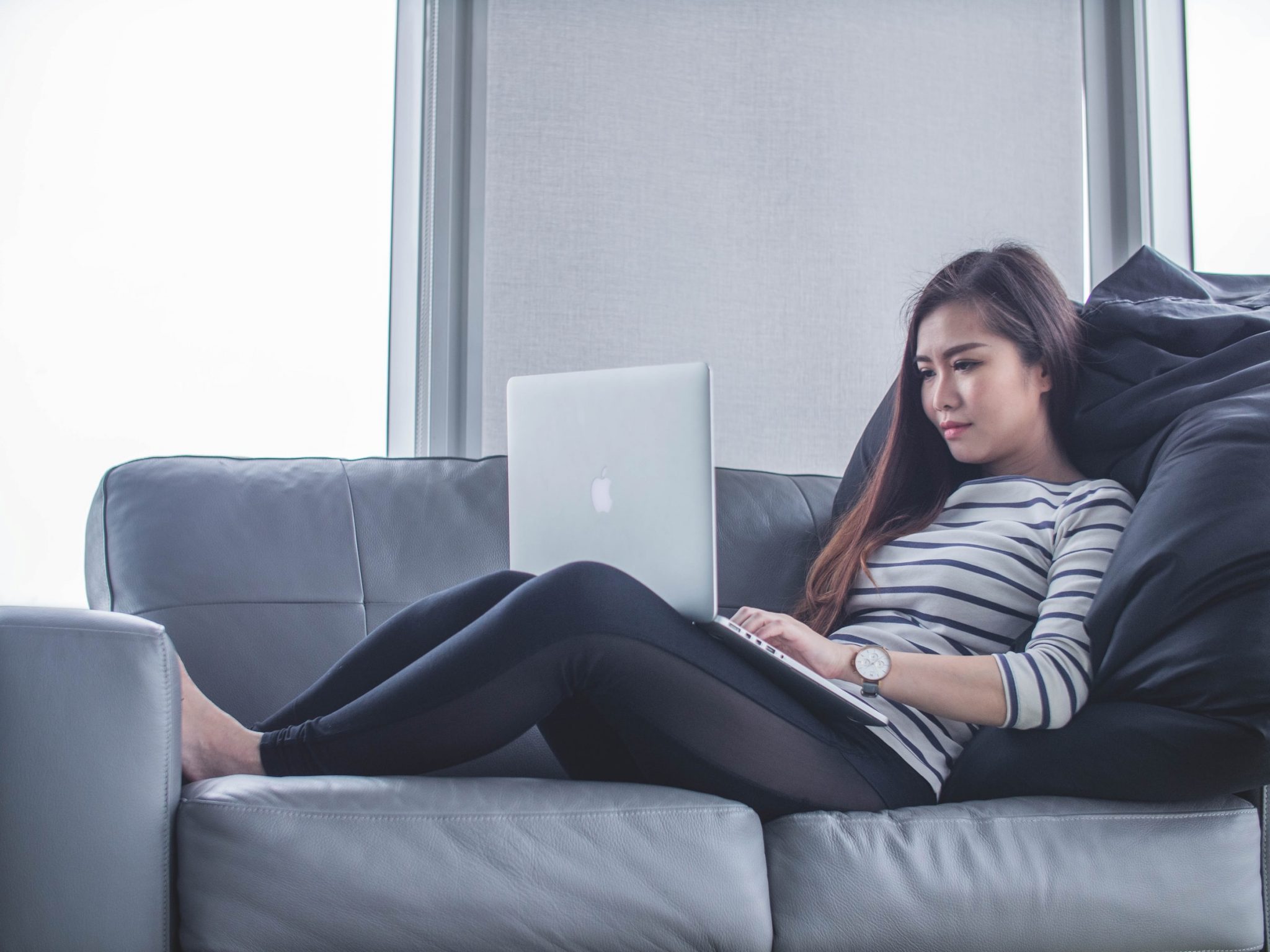woman-lying-down-on-a-sofa-working-on-a-laptop