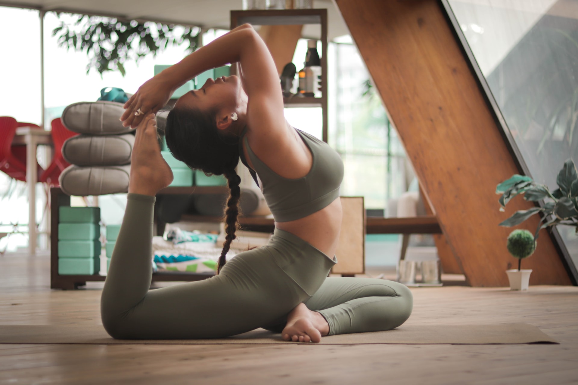 woman-in-workout-gear-holding-a-yoga-pose-on-the-floor-with-her-foot-bent-towards-her-head